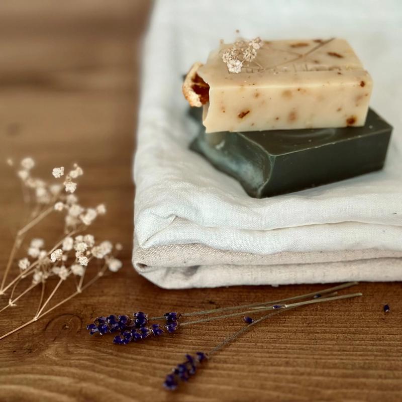 Two handmade natural soap bars stacked on folded linen with dried lavender and botanicals – eco-friendly artisan soap for sensitive skin UK.