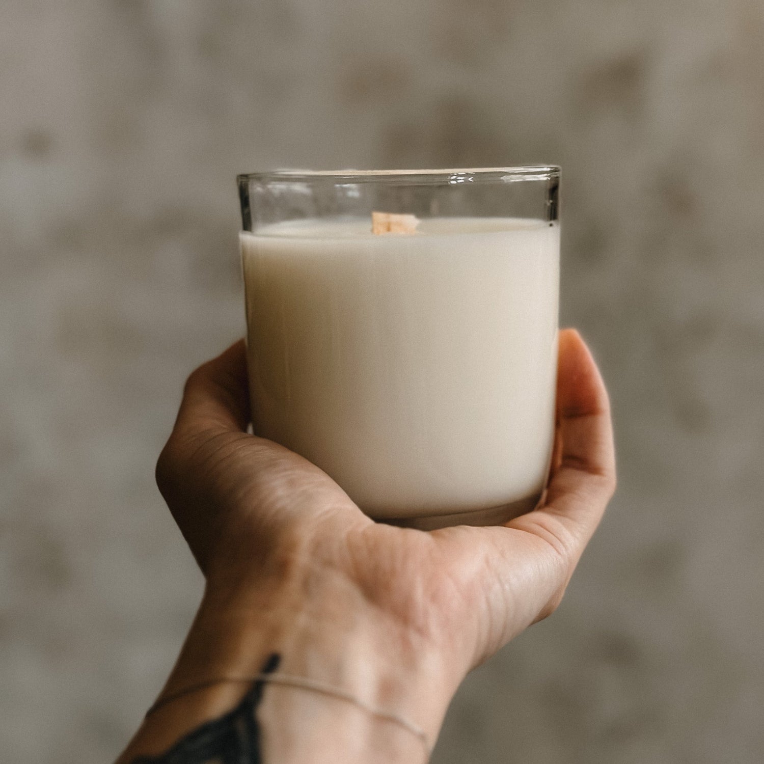 woman's hand holding a candle in a clear glass vessel