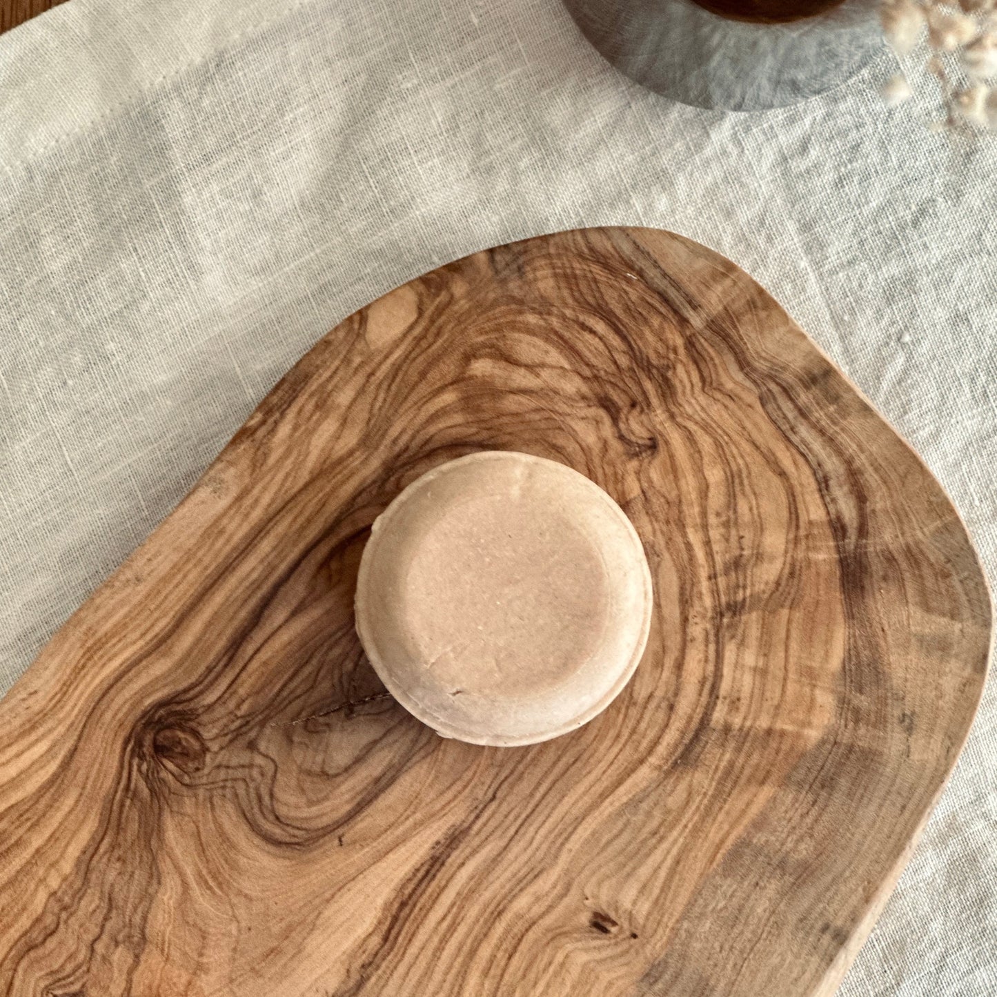 pink solid shampoo bar on olive wood board