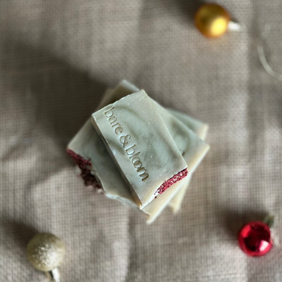 Two soap bars with 'Bare & Bloom' branding on a textured fabric background.