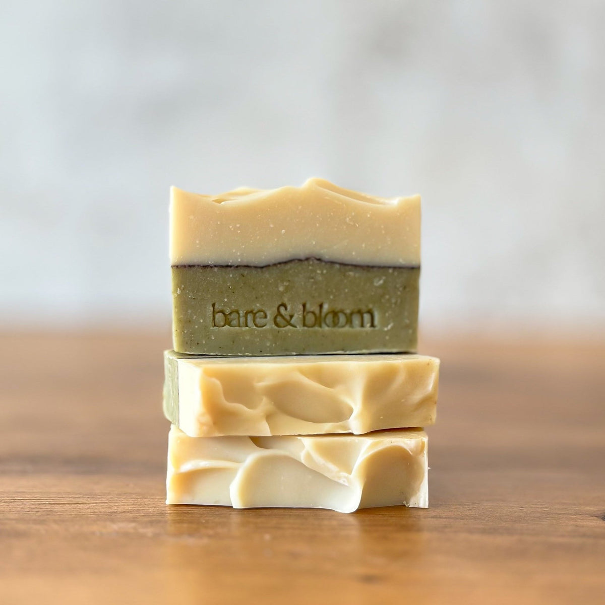 Frost and Fir soap bar with a cream top and sage green base, stamped with the bare & bloom logo